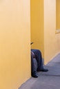 Unrecognizable black man sitting on yellow house front steps looking at phone screen Royalty Free Stock Photo