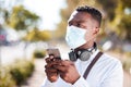 Unrecognizable black man wearing a mask to protect himself from the corona virus pandemic while wearing earphones and Royalty Free Stock Photo