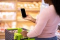 Unrecognizable black woman holding smartphone with blank screen at supermarket, mockup for shopping list app design Royalty Free Stock Photo