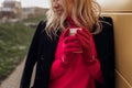 Unrecognizable blond ladylike woman warm, basking with hot cup of tea or coffee on cold balcony. Degradable, zero waste