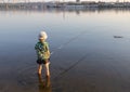 unrecognizable boy fishes standing with fishing rods in the water of the river Royalty Free Stock Photo