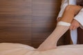 Unrecognizable bride in a silk robe with beautiful slim legs is putting on stockings. Wedding morning preparation Royalty Free Stock Photo