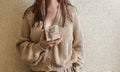 An unrecognizable brunette girl in a beige sweater holds a Christmas gift in eco packaging in her hands. Royalty Free Stock Photo