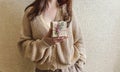 An unrecognizable brunette girl in a beige sweater holds a Christmas gift in eco packaging in her hands. Royalty Free Stock Photo
