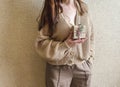 An unrecognizable brunette girl in a beige sweater holds a Christmas gift in eco packaging in her hands. Royalty Free Stock Photo