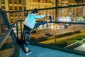 Unrecognizable brunette woman athlete stretching her legs over bridge railing before run at night Royalty Free Stock Photo