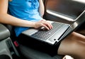 Unrecognizable businesswoman sitting in car with laptop computer on her knees