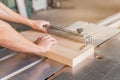 Unrecognizable carpenter sawing wooden plank in workshop