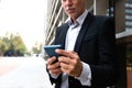Unrecognizable caucasian man using mobile phone outside the office. Copy space. Selective focus on hands. Royalty Free Stock Photo