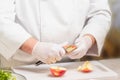 Unrecognizable chef in uniform cutting an apple on a plastic cutting board Royalty Free Stock Photo