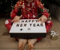unrecognizable child in christmas pajamas holds a sign with congratulations Happy New Year
