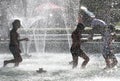 Unrecognizable Children Are Playing In A Fountain Under The Water In The Summer Heat