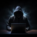 Unrecognizable computer hacker with a black sweatshirt in front of a laptop. Computer hacking concept