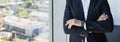 Unrecognizable confident mature businessman with folded arms standing in office near window, panorama, copy space