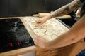 Unrecognizable man arms with tattoo making circle dough samples for baking pies in oven in kitchen. Domestic cuisine Royalty Free Stock Photo