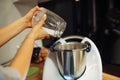 Unrecognizable cropped woman hands adding white sugar powder to steel mixer or blender bowl. Modern kitchen utensil