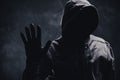 Unrecognizable cyber criminal or computer hacker wearing black hooded jacket, low key portrait