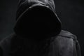 Unrecognizable cyber criminal or computer hacker wearing black hooded jacket, low key portrait