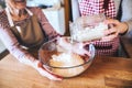 An elderly grandmother with an adult granddaughter at home, baking.