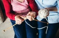 An unrecognizable elderly grandmother and adult granddaughter at home, knitting.