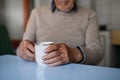 Unrecognizable elderly man with cup of tea sitting indoors at home, resting.