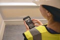 Unrecognizable female civil engineer calculating with a calculator in a construction site, wears yellow high visibility vest Royalty Free Stock Photo