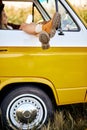 Unrecognizable female in orange boots travelling on yellow mini van, in field Royalty Free Stock Photo