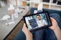 Unrecognizable female patient having video chat with male doctor on digital tablet at home, getting online consultation Royalty Free Stock Photo