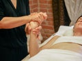 close-up masseuse doing hands relaxing massage to young caucasian woman in spa center wood cabin Royalty Free Stock Photo