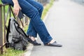 Unrecognizable female sitting on steel fence of pedestrian pathway with mobile phone in hands, urban backpack standing on earth Royalty Free Stock Photo