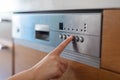 Unrecognizable female turning on dishwasher machine in kitchen Royalty Free Stock Photo