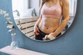 Unrecognizable fit woman with perfect abdominal muscles and obliques in front of mirror look at her reflection