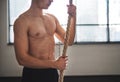 Fit young man in gym standing topless , holding climbing rope. Royalty Free Stock Photo