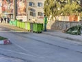 An unrecognizable garbage man looking behind near refuse skips and a bus station. Royalty Free Stock Photo