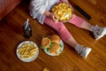 unrecognizable girl eat crispy delicious potato chips and fast food sitting on floor Royalty Free Stock Photo