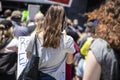 Unrecognizable girl with long hair and tshirt holding sign and taking phone pics at BLM protest surrounded by blurred out