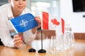 Unrecognizable girl sets midget flags of Canada and NATO before international negotiations