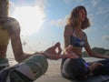Unrecognizable girls practice meditation sitting in lotus pose at sandy shore