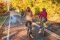 Unrecognizable girls riding bike, autumn park, bright colorful trees, sunny day, fall foliage background. Healthy Royalty Free Stock Photo