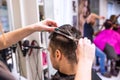 Unrecognizable hairdresser cutting hair of her young client. Royalty Free Stock Photo