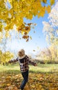 unrecognizable happy child, junior schoolboy playing outdoors in autumn among bright autumn leave