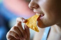 Unrecognizable happy teenage girl biting spicy nacho chip at home