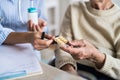 An unrecognizable health visitor explaining a senior woman in wheelchair how to take pills. Royalty Free Stock Photo