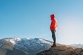 Unrecognizable hiker dressed in a red coat standing on top of a snowy mountain looking at the view Royalty Free Stock Photo