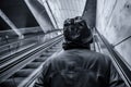 Unrecognizable hooded person on moving escalator