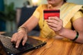 Unrecognizable Indian woman hoilding credit card and entering card details into laptop for online e-commerce shopping or bill