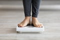 Unrecognizable Indian woman standing on scales, checking her weight indoors, closeup of feet Royalty Free Stock Photo