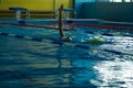 unrecognizable kid swimming freestyle style training in swimmer pool with splashing water.