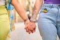 Unrecognizable lesbian couple holding hands with LGBTQ flag bracelets and pin. Royalty Free Stock Photo