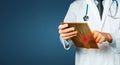 Unrecognizable male doctor in a white lab coat with a stethoscope uses a tablet, using a digital patient support system, test resu